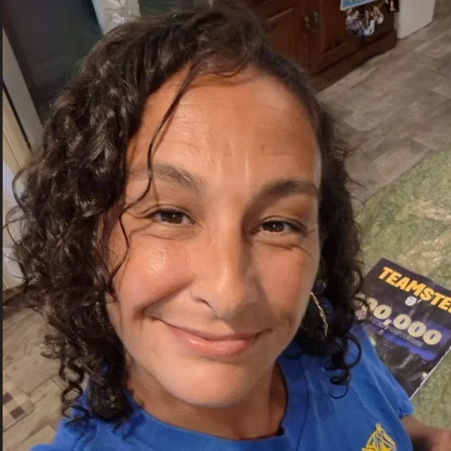 Amy Goldstein, smiling, in a blue Teamsters t-shirt.
